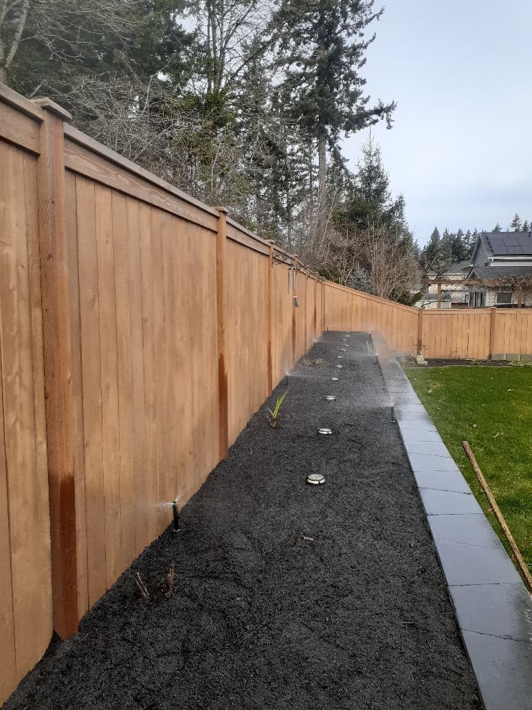 Cedar fence with sprinkler system and ground lights