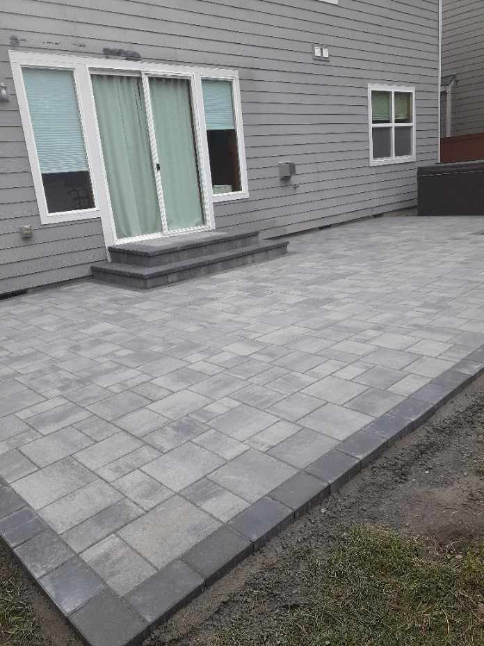Large gray paver patio installation with stepping stones